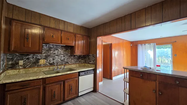 a kitchen with stainless steel appliances wooden cabinets a sink and a large window