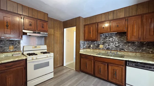 a kitchen with stainless steel appliances granite countertop wooden cabinets stove top oven and granite counter top
