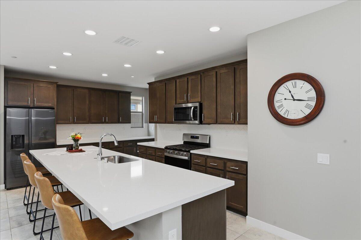 73721 Raphael Drive Palm Desert, CA 92211 - Photo 17 of 54 a kitchen with stainless steel appliances a stove a sink a microwave and cabinets