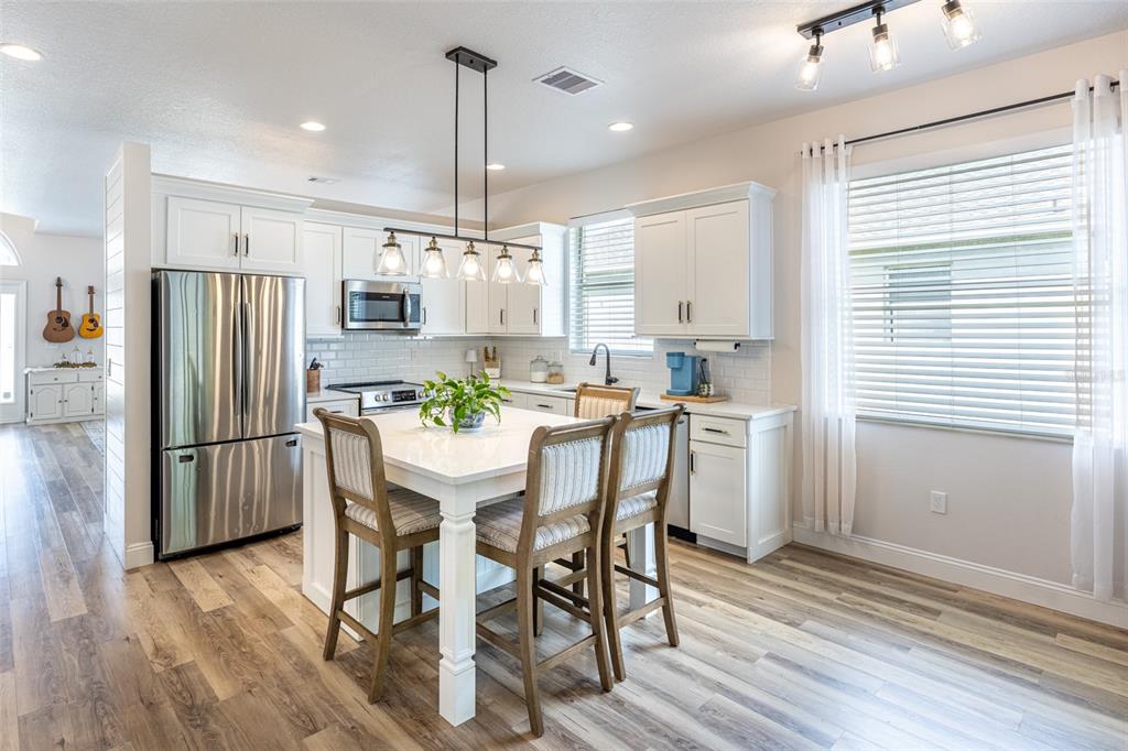 4136 Little Gap Loop Ellenton, FL 34222 - Photo 3 of 50 a kitchen with stainless steel appliances a dining table chairs refrigerator microwave and cabinets