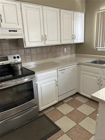 a kitchen with granite countertop white cabinets and appliances