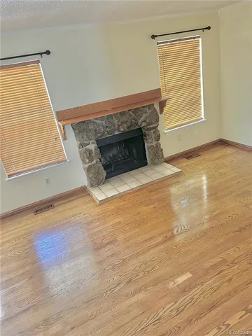 an empty room with wooden floor and fireplace