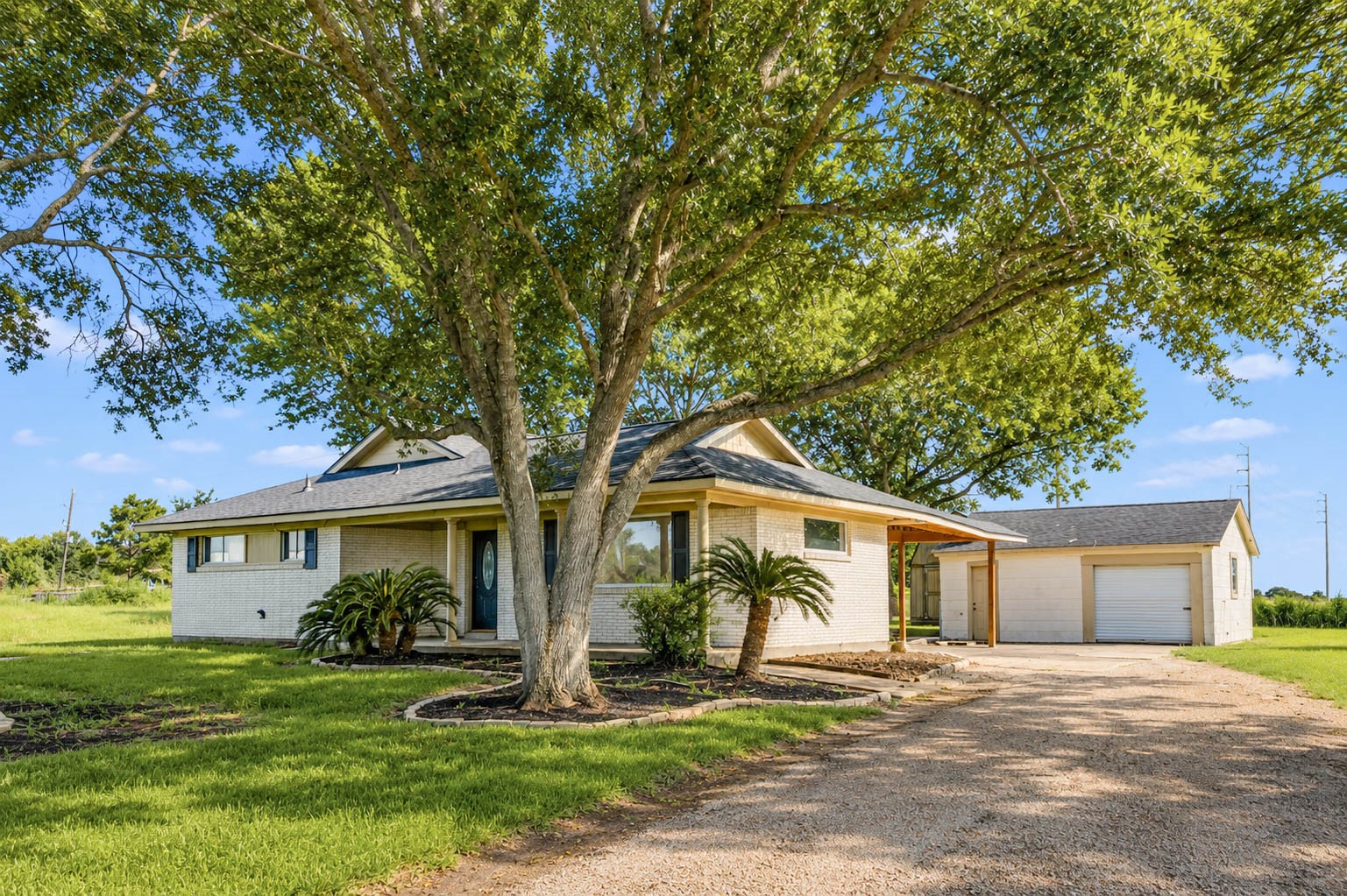 925 Norcross Road Wallis, TX 77485 - Photo 42 of 46 A long driveway leads to this beautifully maintained residence, where the covered front porch is framed by stately columns and the classic white brick exterior blends seamlessly with the natural beauty of the surrounding acreage.