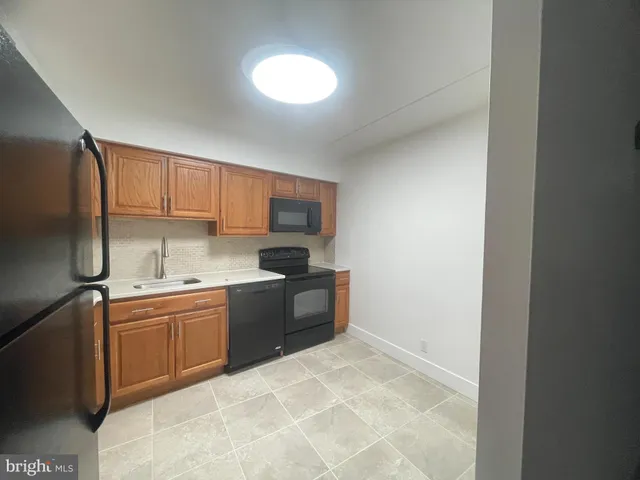 a kitchen with stainless steel appliances a sink a stove a refrigerator cabinets and a window