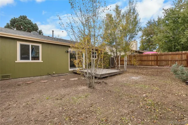 a view of backyard with wooden fence and a large tree