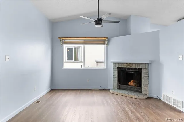 a view of empty room with wooden floor and fireplace