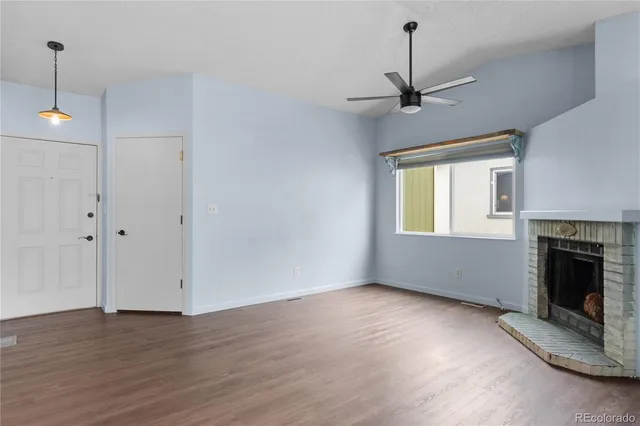 a view of an empty room with wooden floor fireplace and a window