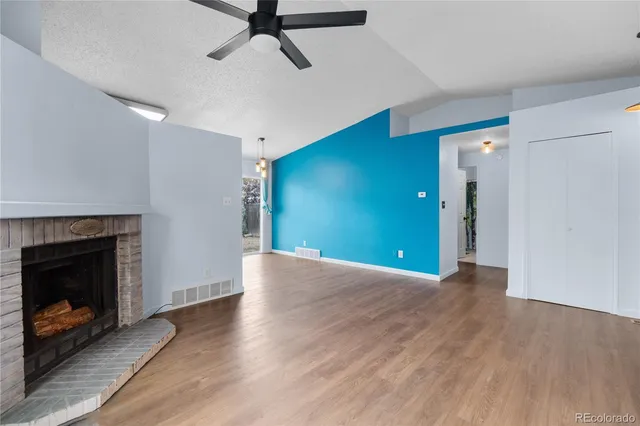a view of a room with wooden floor a fireplace and window