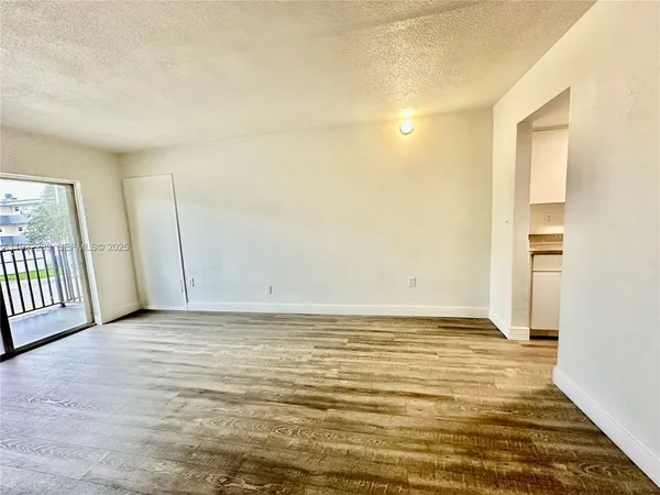 a view of an empty room with window and wooden floor