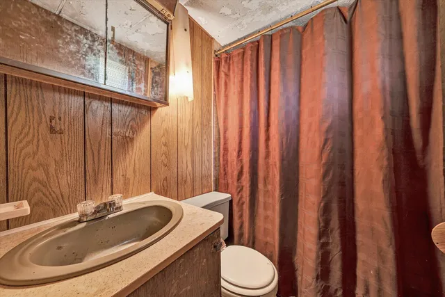 a bathroom with a sink a toilet a mirror and shower curtain