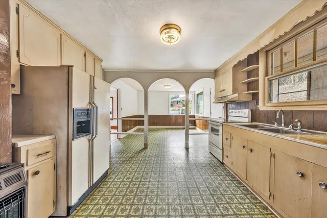 a large white kitchen with stainless steel appliances granite countertop a refrigerator and a sink