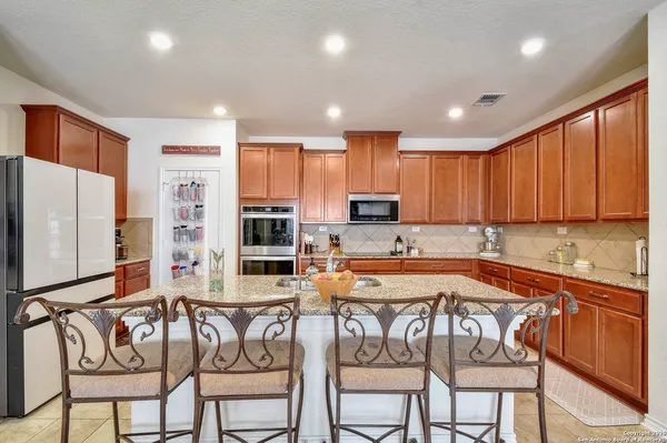 a kitchen with stainless steel appliances granite countertop a table chairs sink and cabinets
