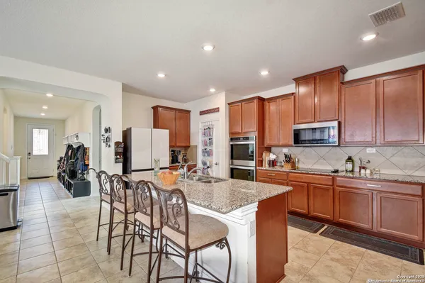 a kitchen with stainless steel appliances granite countertop table chairs sink and wooden cabinets