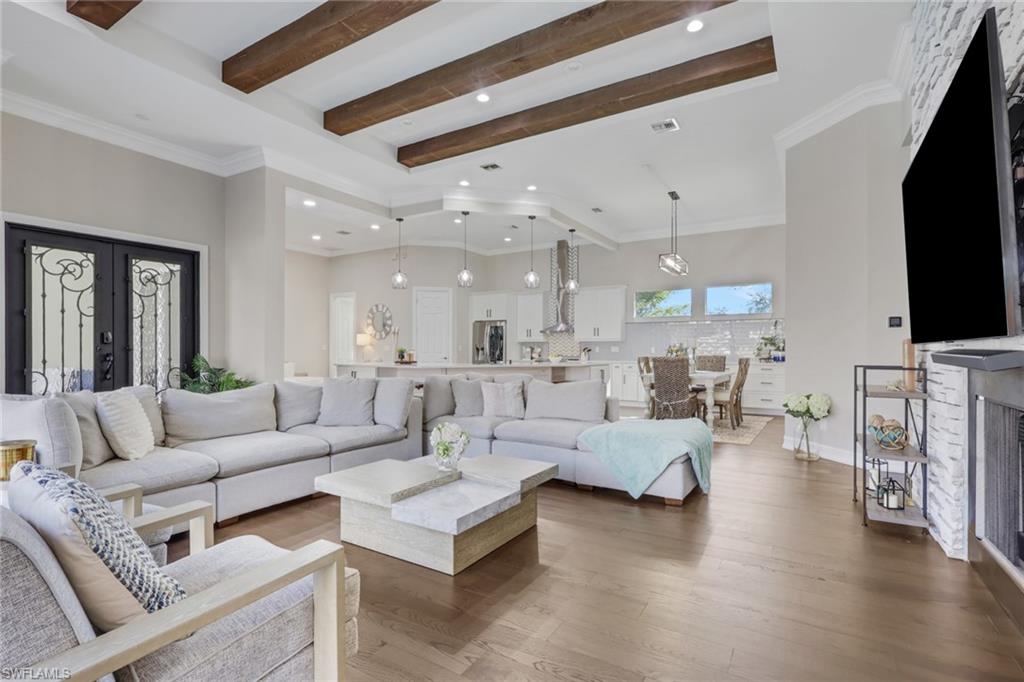 5074 Rustic Oaks Circle Naples, FL 34105 - Photo 12 of 38 Living room with crown molding, wood finished floors, beam ceiling, french doors, and recessed lighting