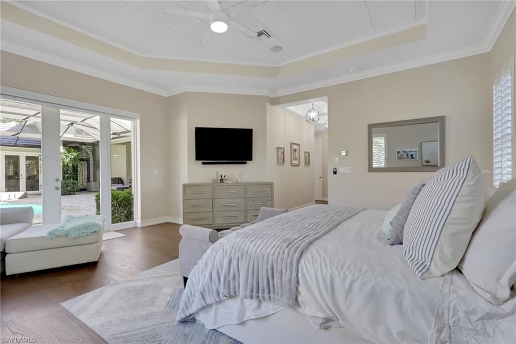 5074 Rustic Oaks Circle Naples, FL 34105 - Photo 18 of 38 Bedroom featuring wood-type flooring, a raised ceiling, access to exterior, crown molding, and ceiling fan