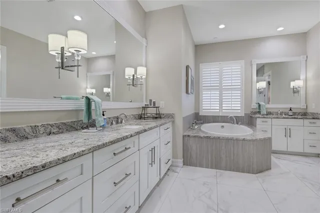 a bathroom with a granite countertop double vanity sink a bathtub and shower
