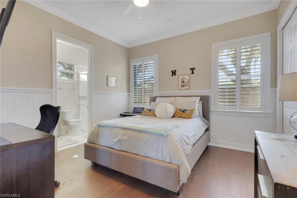5074 Rustic Oaks Circle Naples, FL 34105 - Photo 21 of 38 Bedroom featuring wainscoting, wood finished floors, ornamental molding, ceiling fan, and ensuite bath