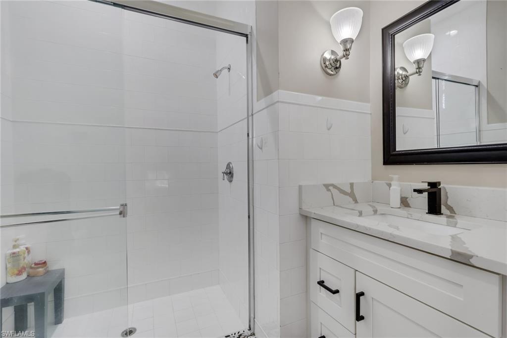 5074 Rustic Oaks Circle Naples, FL 34105 - Photo 24 of 38 a bathroom with a granite countertop sink a mirror and shower