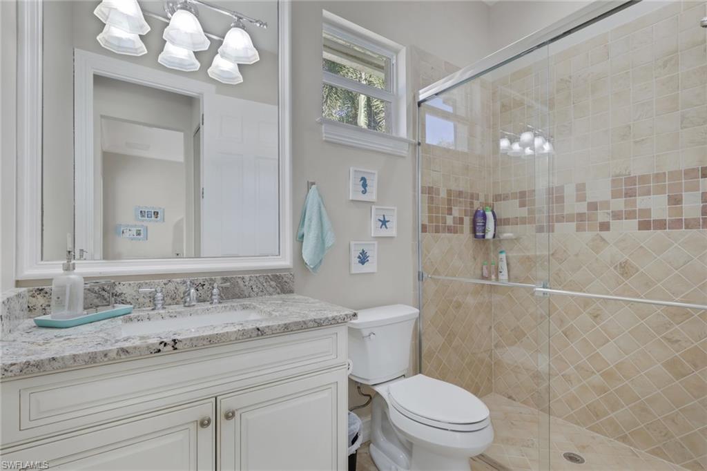 5074 Rustic Oaks Circle Naples, FL 34105 - Photo 28 of 38 a bathroom with a granite countertop sink a toilet and a mirror