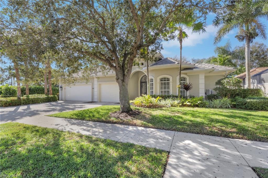 5074 Rustic Oaks Circle Naples, FL 34105 - Photo 3 of 38 View of front of property featuring a front lawn, stucco siding, concrete driveway, and a tile roof