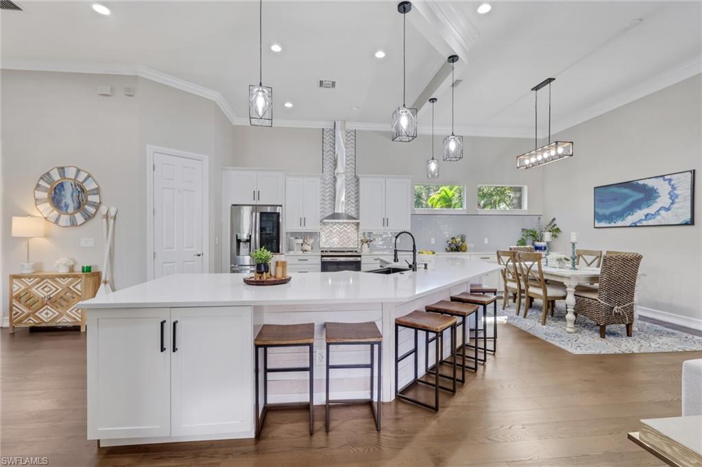 5074 Rustic Oaks Circle Naples, FL 34105 - Photo 7 of 38 a kitchen with stainless steel appliances kitchen island granite countertop a table chairs and a refrigerator