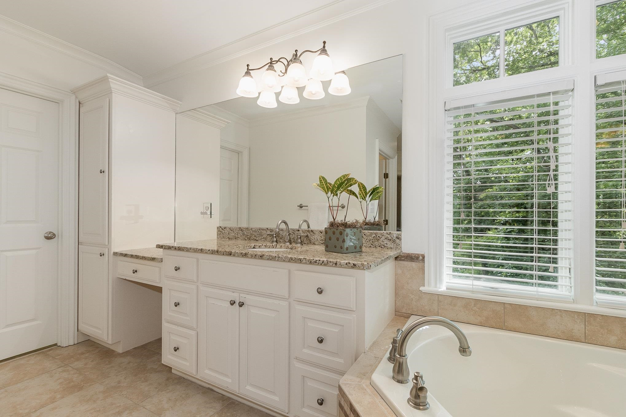 3327 Landor Road Raleigh, NC 27609 - Photo 36 of 60 a bathroom with a granite countertop sink a large mirror a bathtub and window