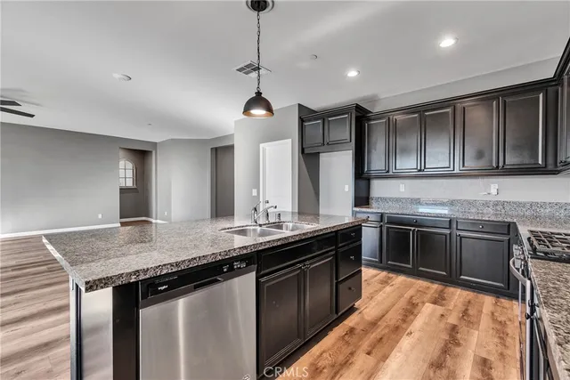 a kitchen with stainless steel appliances granite countertop a sink a stove and a wooden floors
