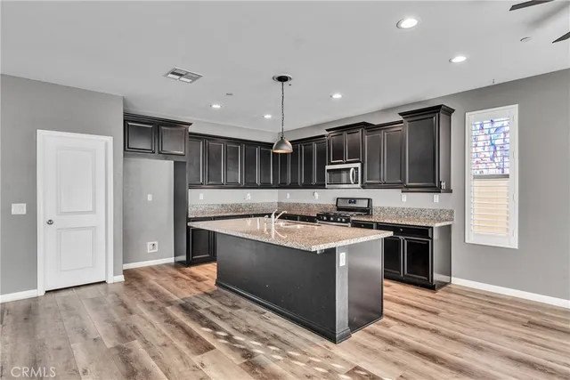 a kitchen with kitchen island stainless steel appliances a sink cabinets and wooden floor
