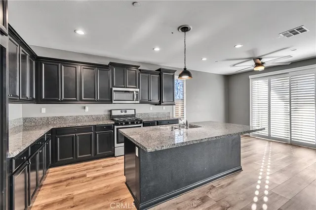 a large kitchen with granite countertop a stove top oven a sink dishwasher a dining table and chairs with wooden floor