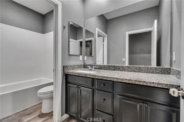 a bathroom with a granite countertop toilet sink and mirror