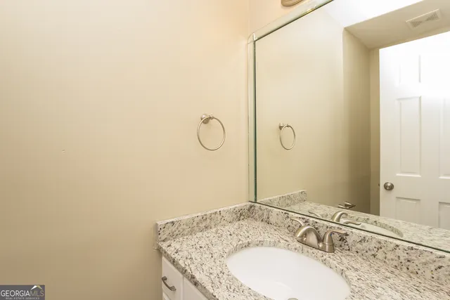 a bathroom with a granite countertop sink and a mirror