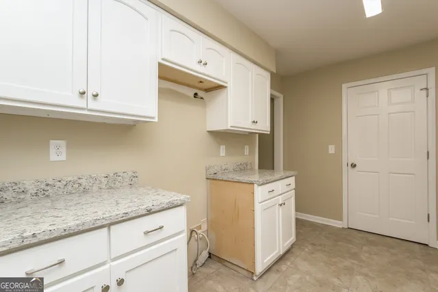 a kitchen with granite countertop white cabinets and a sink