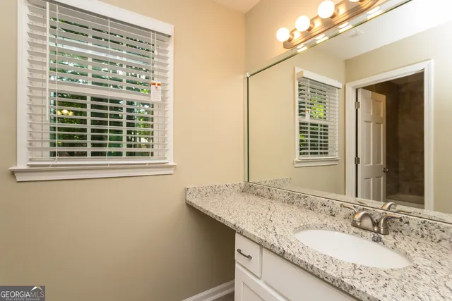 a bathroom with a granite countertop sink and a window