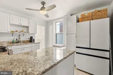 a kitchen with stainless steel appliances granite countertop a refrigerator a sink and white cabinets