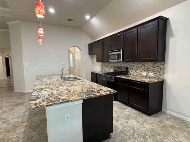 a kitchen with kitchen island granite countertop wooden cabinets and stainless steel appliances