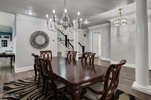 a dining room with wooden floor a chandelier a wooden table and chairs