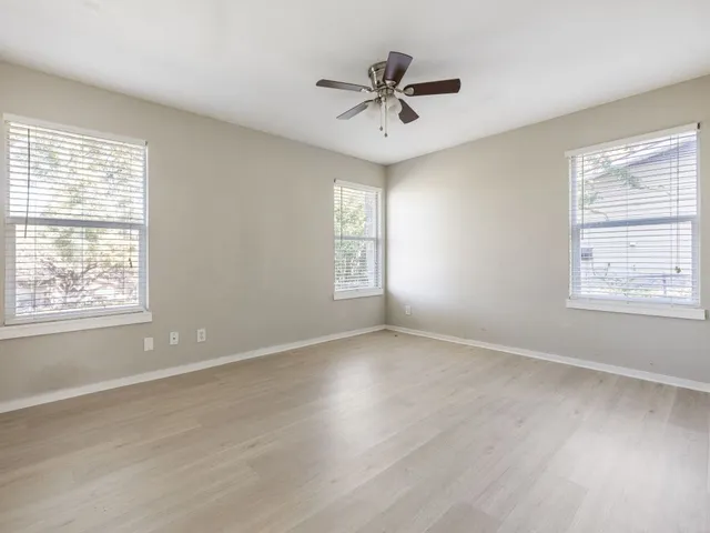 a view of an empty room with a window and wooden floor