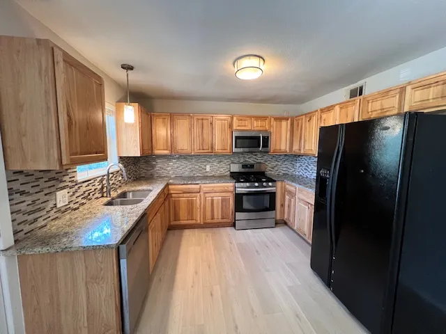 a kitchen with granite countertop a refrigerator stove and sink