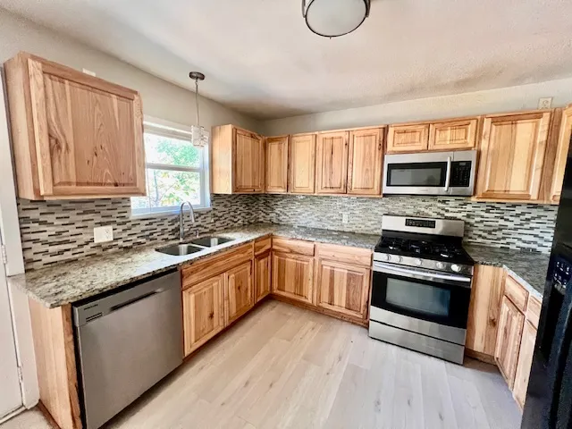 a kitchen with granite countertop a stove top oven a sink dishwasher and a microwave oven with cabinets