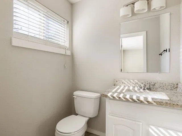 a bathroom with a granite countertop toilet sink and mirror