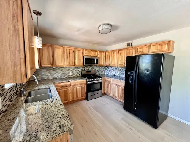 a kitchen with granite countertop a refrigerator stove top oven and sink