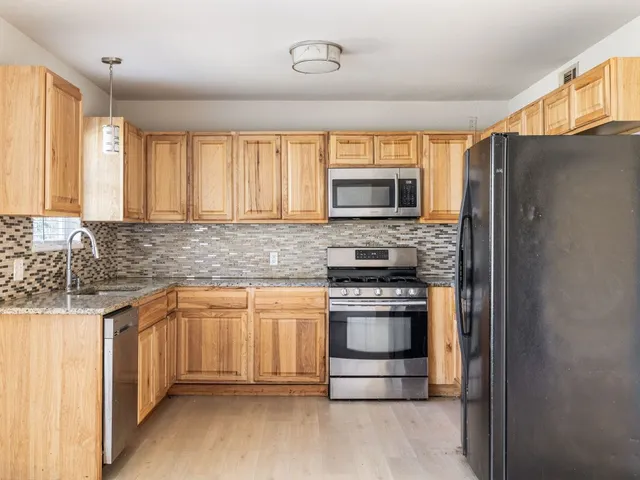 a kitchen with stainless steel appliances granite countertop a refrigerator a stove a sink and a microwave