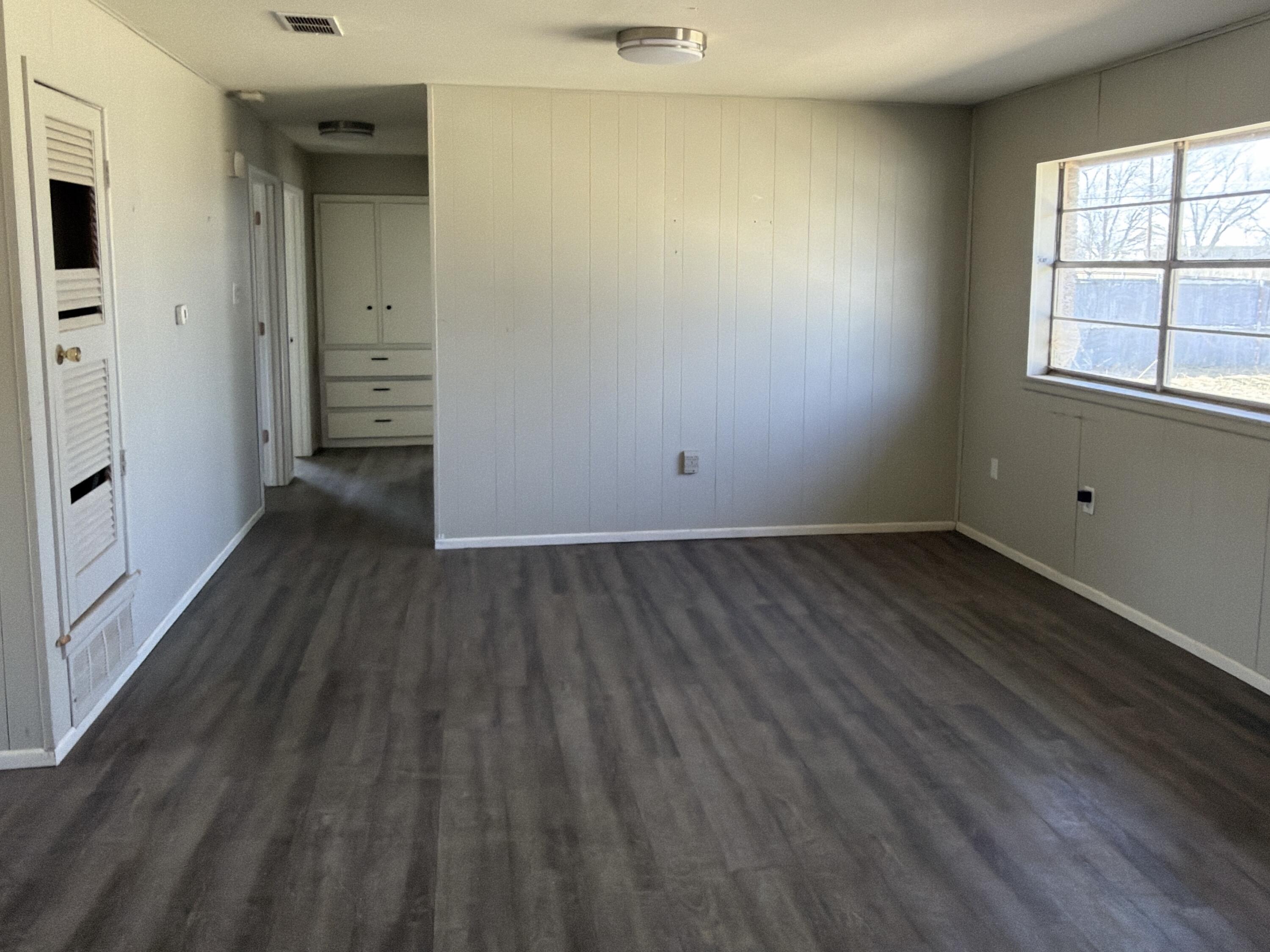 307 East 5th Street Sundown, TX 79372 - Photo 3 of 14 an empty room with wooden floor and windows