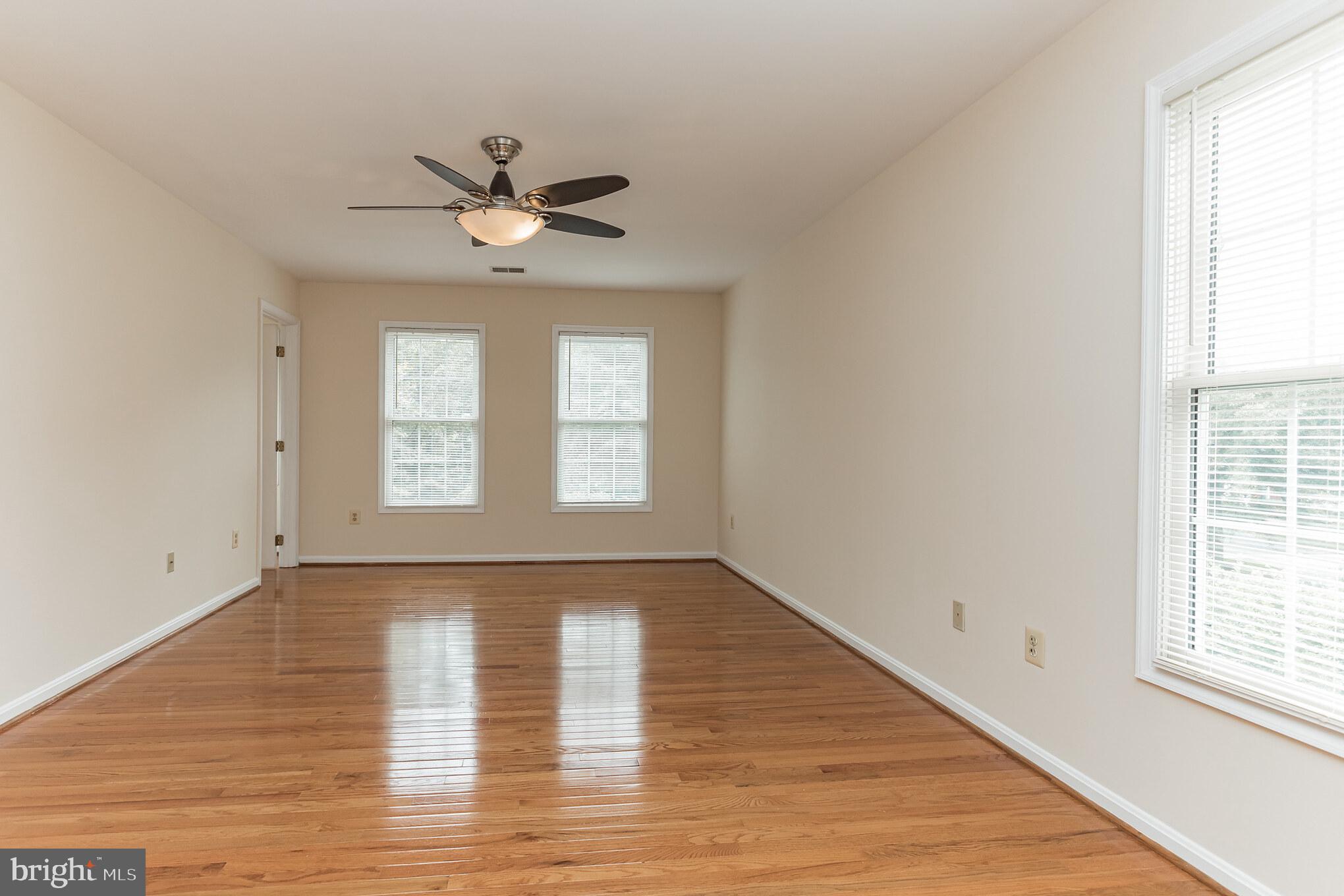 13907 Willow Tree Drive Rockville, MD 20850 - Photo 16 of 30 an empty room with wooden floor a ceiling fan and windows
