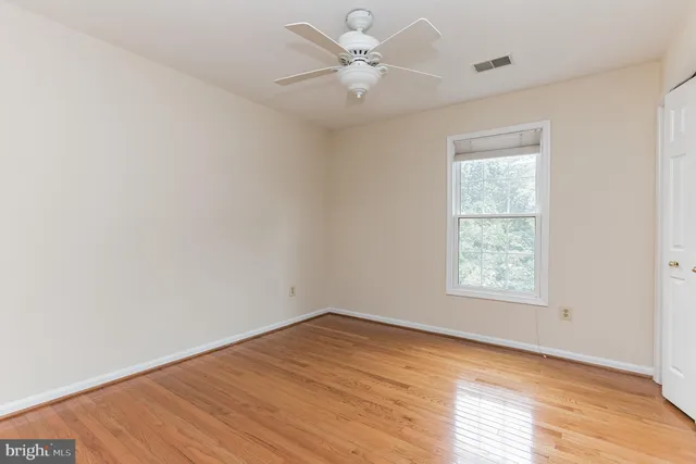 an empty room with a window and a ceiling fan