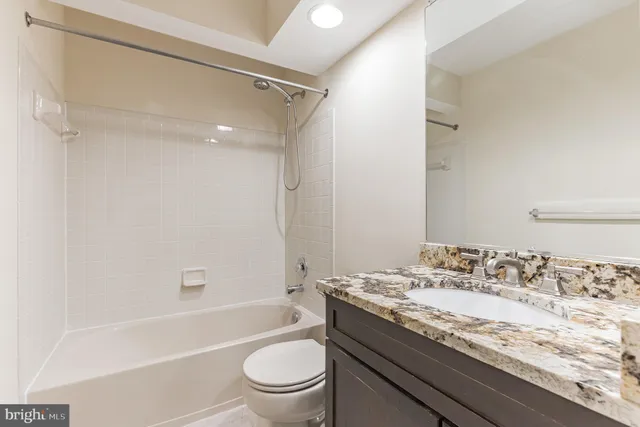 a bathroom with a granite countertop sink a toilet and shower