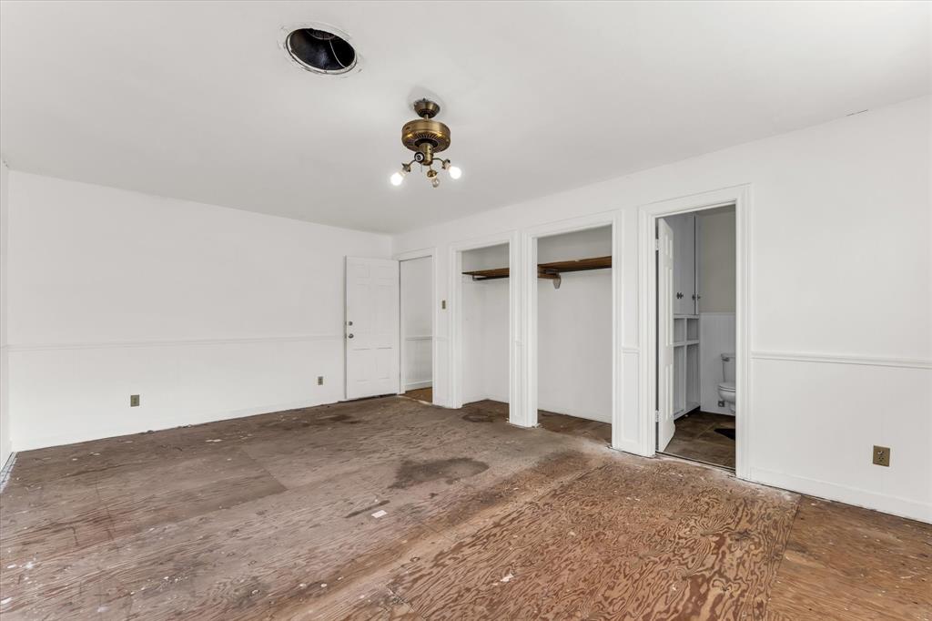 421 Rice Avenue Waco, TX 76708 - Photo 28 of 40 Upstairs at the end of the hallway, white walls with wainscoting, two open closet spaces, a built-in ceiling light fixture, and an interior door
