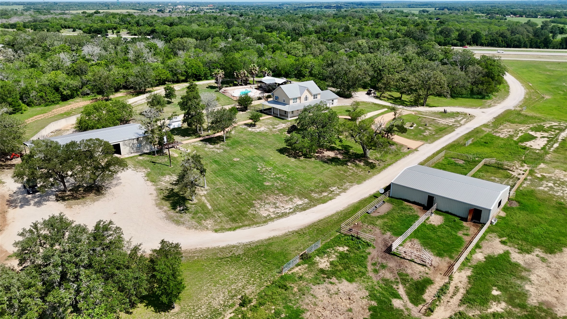 1175 Southern Way Luling, TX 78648 - Photo 2 of 40 An aerial perspective reveals a charming estate with a pool and multiple outbuildings amidst lush, verdant landscapes.