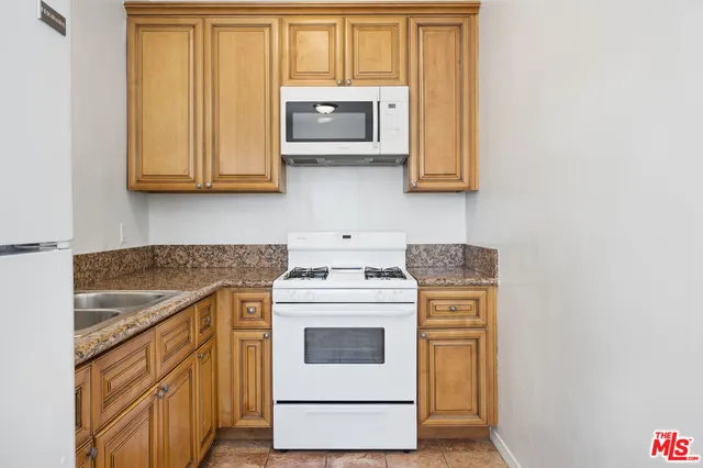 a kitchen with stainless steel appliances granite countertop white cabinets and a stove top oven
