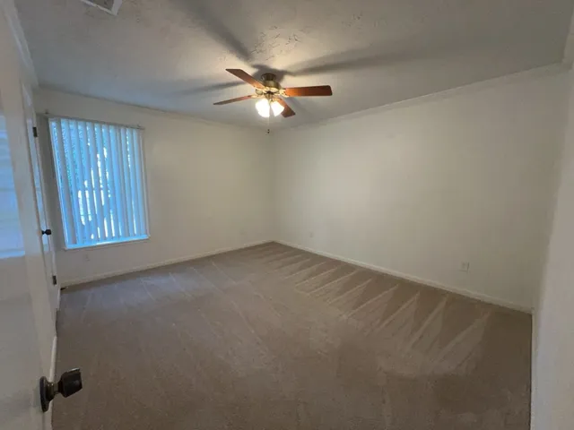 an empty room with windows and fan